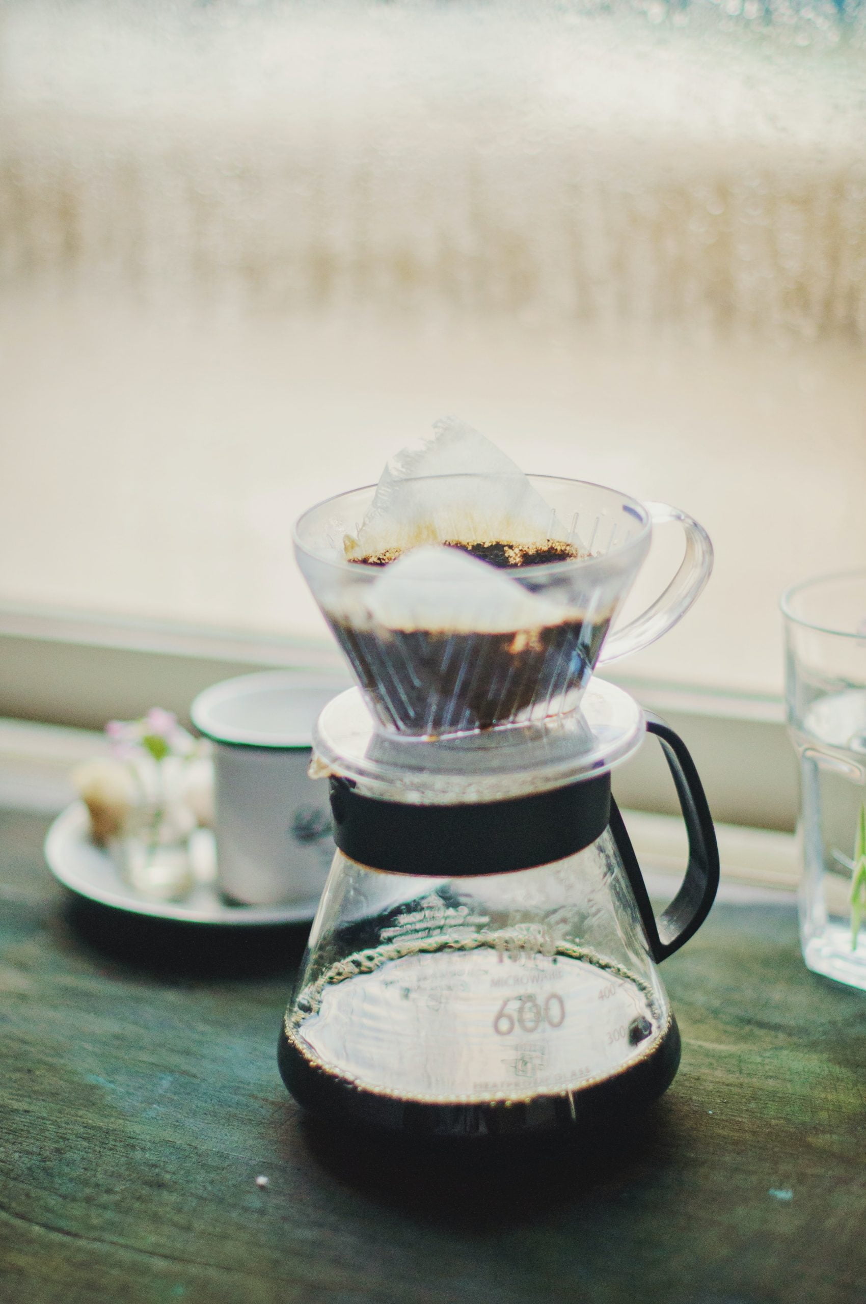 shallow focus photography of pitcher of pour-over coffee brewing.