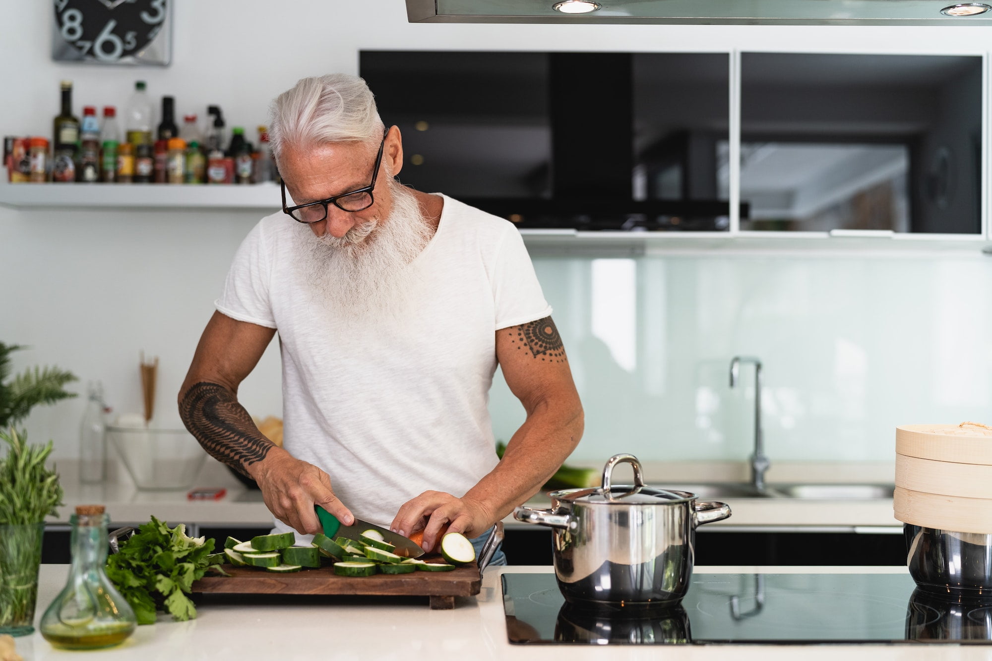 Happy senior man having fun cooking at home - Elderly person preparing health lunch in kitchen